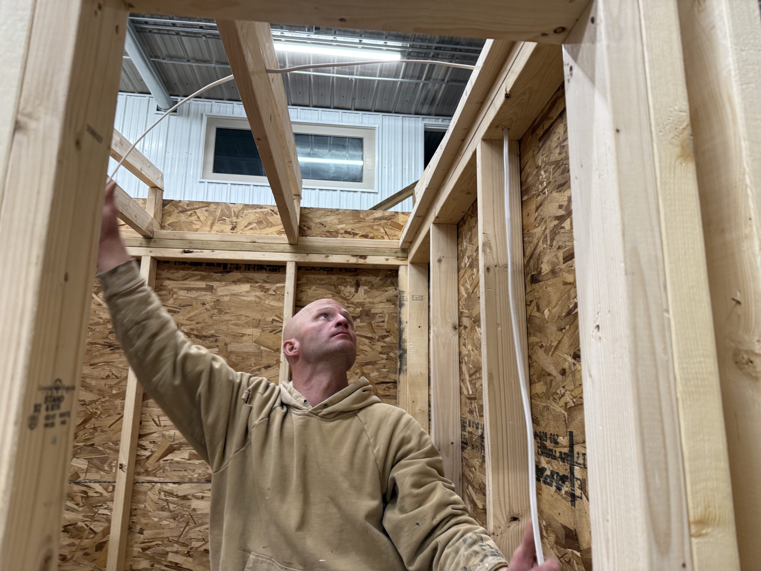 Cedar Sense professionals building and installing an outdoor hobbit sauna pod, detailing panel placement and expert craftsmanship