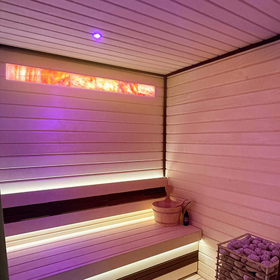 Backlit Himalayan salt wall glowing inside a modern sauna