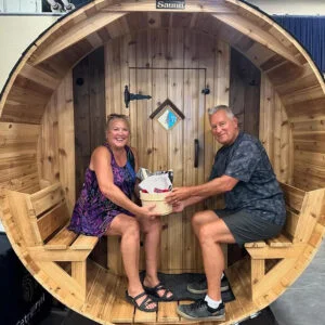 2 people sitting outside barrel sauna