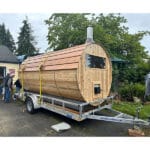 Mobile cedar sauna package with cold plunge tub, outdoor shower, and accessories on display outdoors