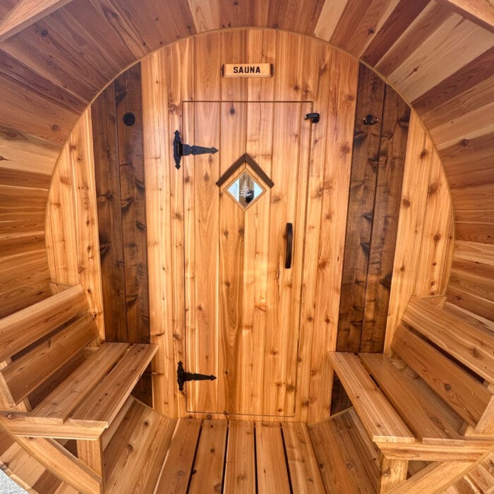 Off-grid wood-fired sauna with rustic log rack and outdoor cold plunge