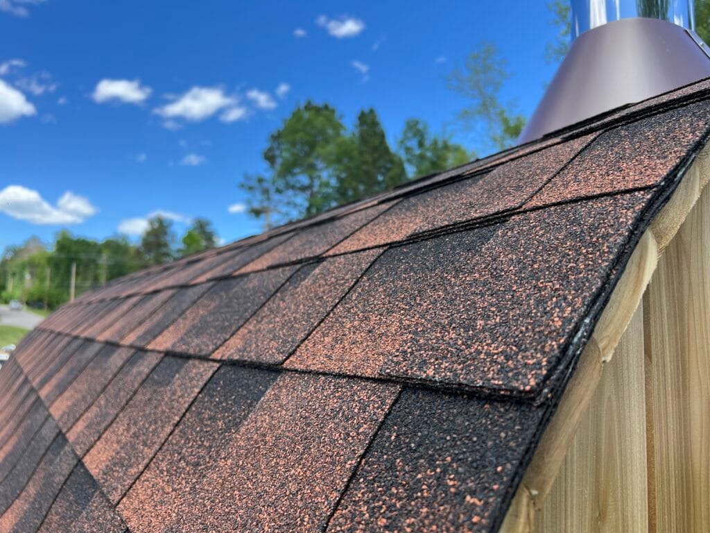 Close-up shot of the barrel sauna roof with shingles/tin in a backyard setting