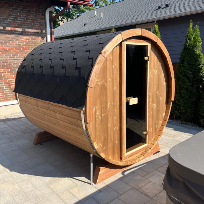 SaunaLife barrel sauna glowing at sunset with interior lighting visible