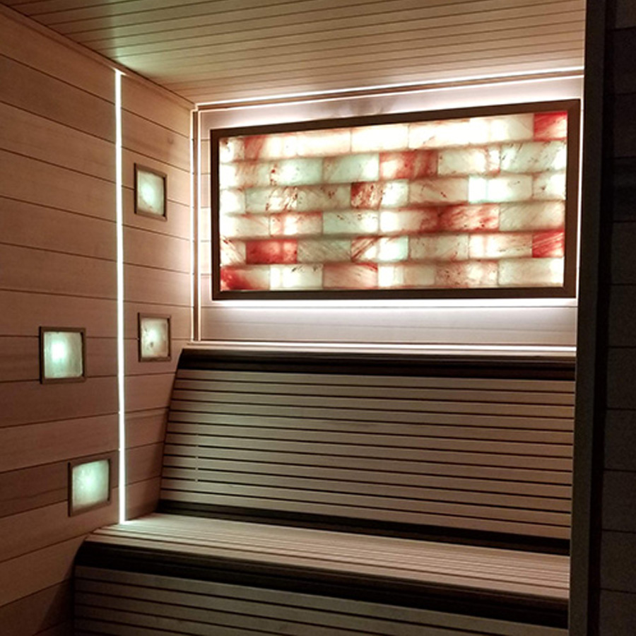 Large Himalayan salt sauna wall glowing with LED lighting inside modern sauna
