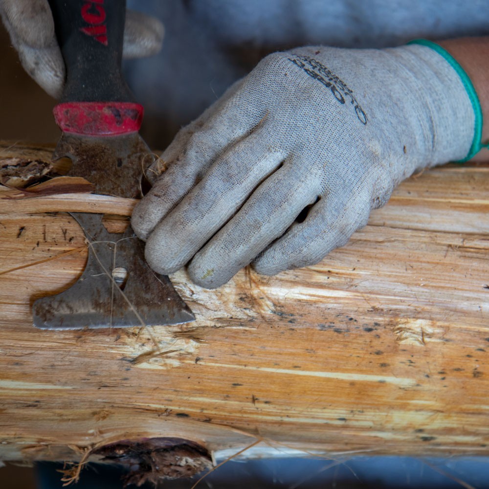 Hand peeling cedar log furniture close-up view