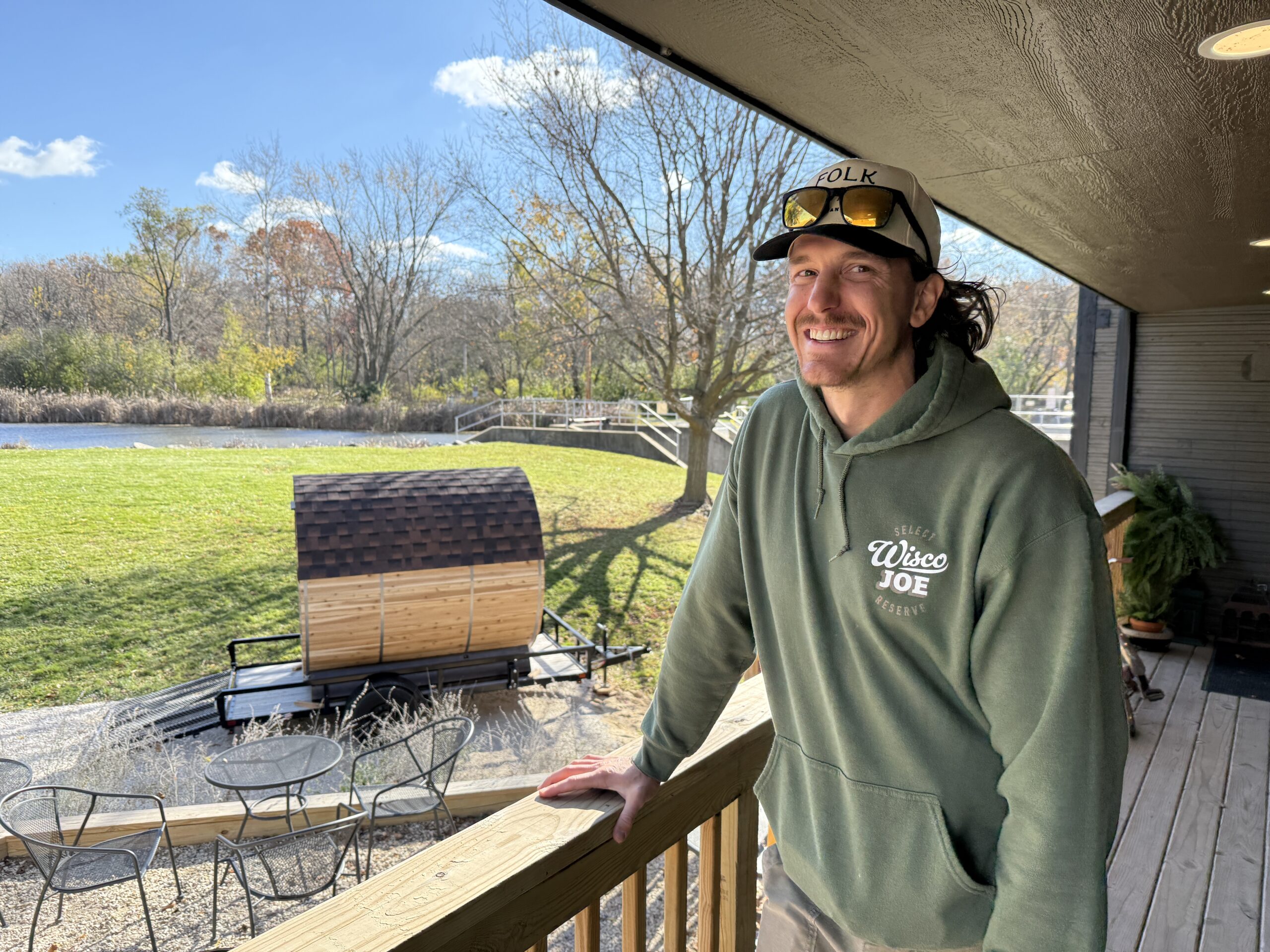 Scott from Folklore standing on the porch with the Cedar Sense barrel sauna behind him