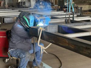 Welder fabricating a steel trailer frame in a Minnesota shop