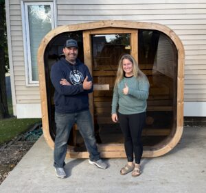 Cedar Sense owner Mike and a customer smiling and giving thumbs up beside a cube sauna